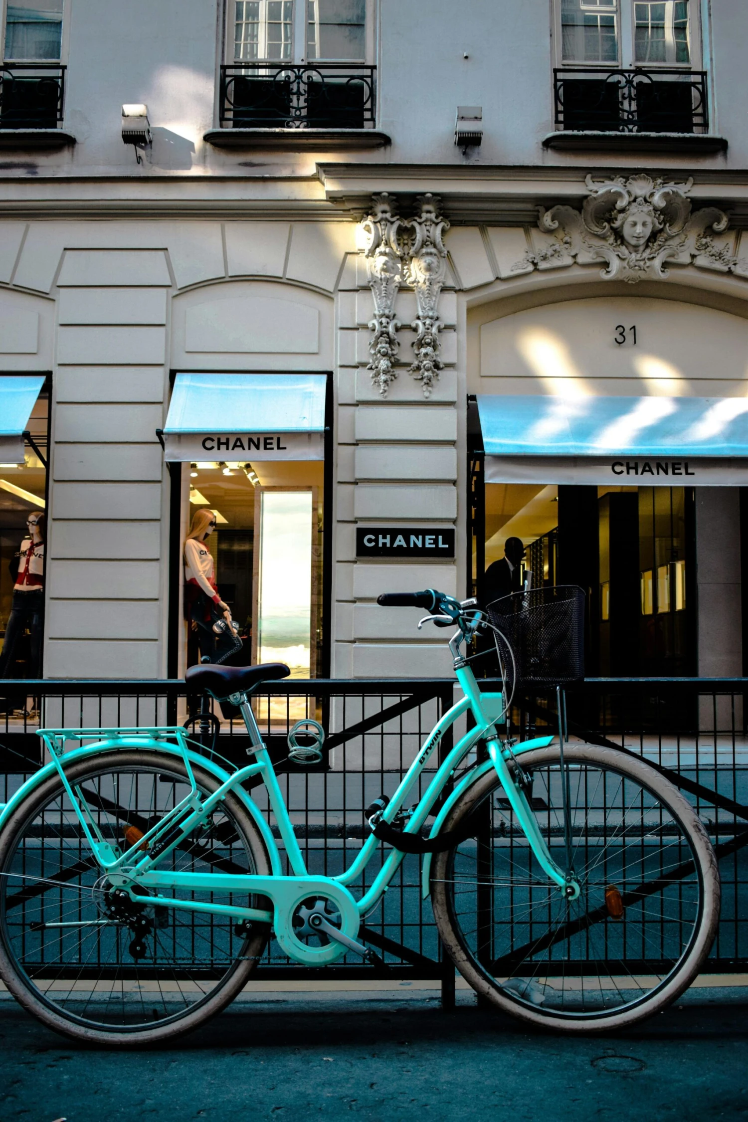 A turquoise bicycle parked in front of a Chanel store in Paris, France.